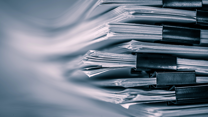 Black and white stack of papers broken up by binder clips