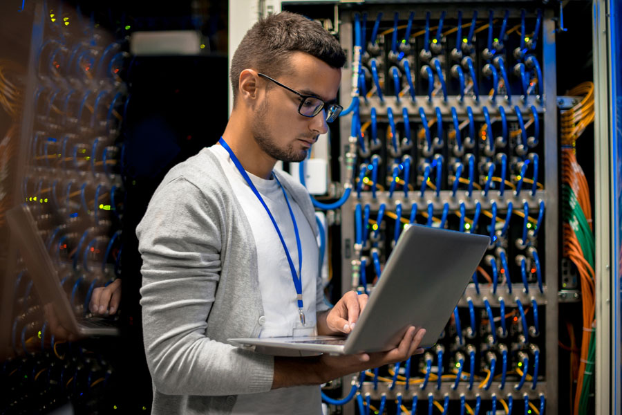 Hardware design engineer works on network optimization while standing in a server room